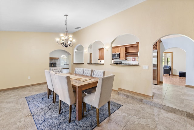 dining space with light tile patterned floors, a chandelier, arched walkways, and baseboards