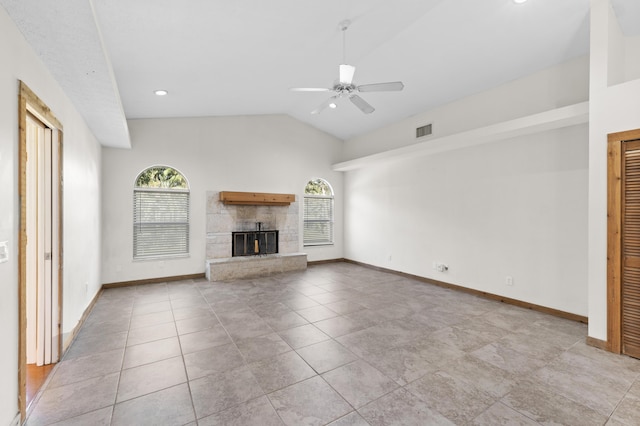 unfurnished living room featuring healthy amount of natural light, lofted ceiling, ceiling fan, a stone fireplace, and baseboards