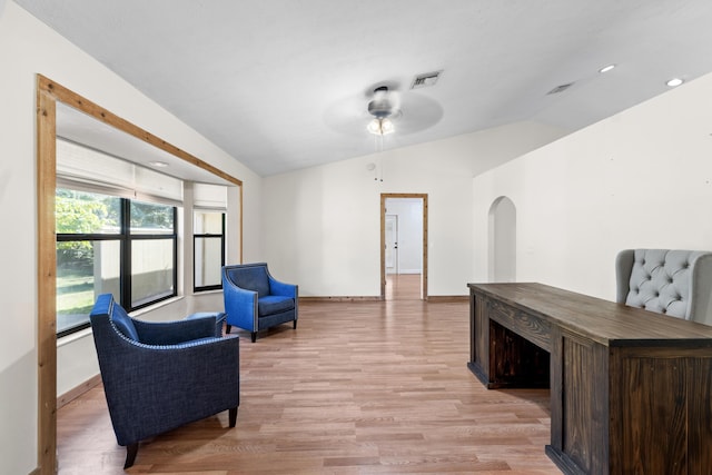 sitting room featuring vaulted ceiling, arched walkways, light wood-style floors, baseboards, and a ceiling fan
