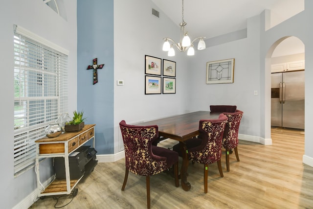 1644 Oak Berry Cir, Wellington, FL 33414 - dining room featuring light wood finished floors, arched walkways, a chandelier, baseboards, and a high ceiling