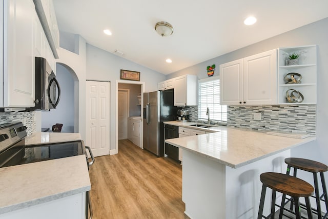 1644 Oak Berry Cir, Wellington, FL 33414 - kitchen with black appliances, a sink, a peninsula, washer and dryer, and a breakfast bar