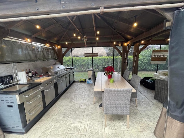 view of patio / terrace with a gazebo, outdoor dining space, a sink, exterior kitchen, and area for grilling
