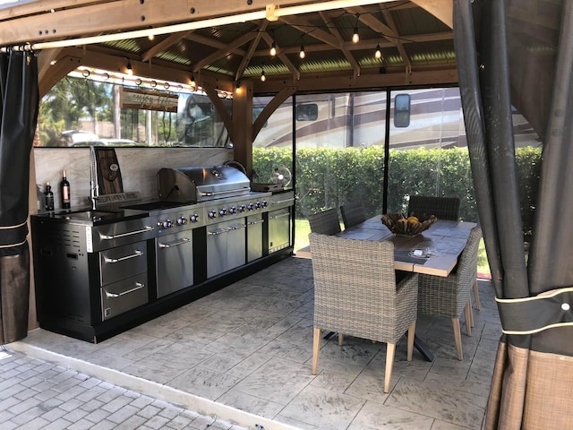 view of patio / terrace with exterior kitchen, a gazebo, outdoor dining area, and area for grilling