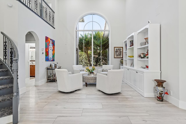 16313 Mira Vista Ln, Delray Beach, FL 33446 - living area featuring stairs, a towering ceiling, arched walkways, light wood-type flooring, and baseboards