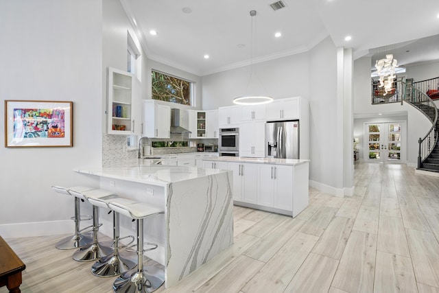 16313 Mira Vista Ln, Delray Beach, FL 33446 - kitchen with a towering ceiling, wall chimney range hood, appliances with stainless steel finishes, a peninsula, and light stone countertops