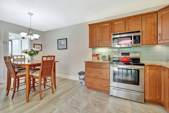 1518 15th Ln, Palm Beach Gardens, FL 33418 - kitchen featuring appliances with stainless steel finishes, brown cabinetry, a chandelier, tasteful backsplash, and a textured ceiling