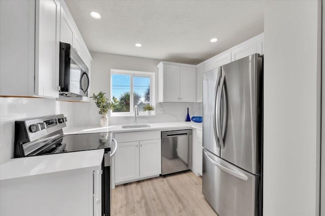 275 Palm Ave Unit B304, Jupiter, FL 33477 - kitchen with stainless steel appliances, a sink, white cabinets, light wood-type flooring, and light countertops