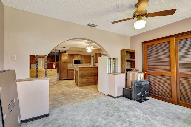 13705 Persimmon Blvd, The Acreage, FL 33411 - kitchen with arched walkways, a ceiling fan, freestanding refrigerator, light countertops, and brown cabinetry