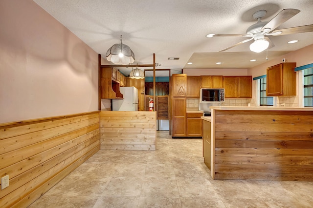 13705 Persimmon Blvd, The Acreage, FL 33411 - kitchen featuring brown cabinetry, ceiling fan, a peninsula, a textured ceiling, and light countertops