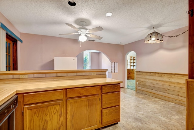 13705 Persimmon Blvd, The Acreage, FL 33411 - kitchen with butcher block counters, a textured ceiling, a ceiling fan, brown cabinetry, and arched walkways