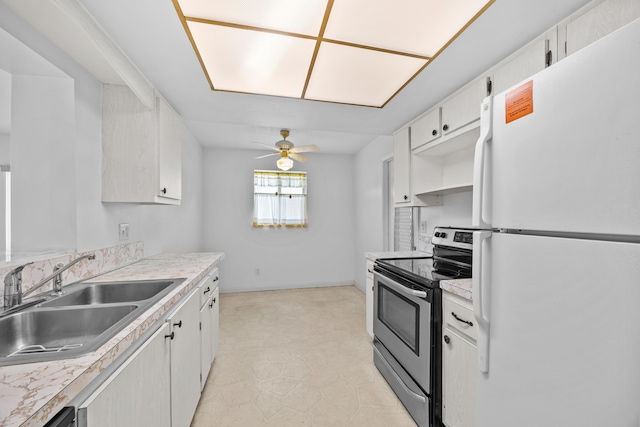 kitchen with freestanding refrigerator, stainless steel range with electric stovetop, a sink, light countertops, and ceiling fan