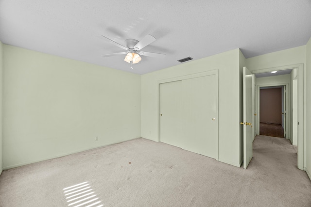 unfurnished bedroom featuring light carpet, a closet, ceiling fan, and a textured ceiling