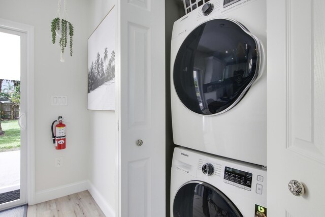 2559 Conroy Dr, North Palm Beach, FL 33403 - washroom featuring stacked washer and clothes dryer, light wood-type flooring, and baseboards