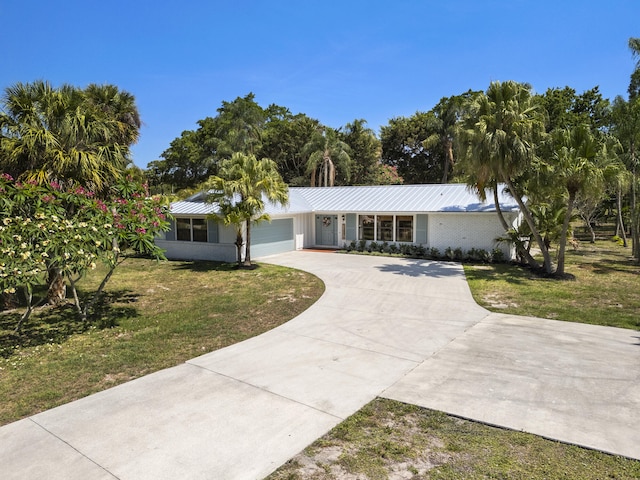 4972 S Kay St, Palm Beach Gardens, FL 33418 - view of front of house featuring a garage, a front yard, concrete driveway, and metal roof