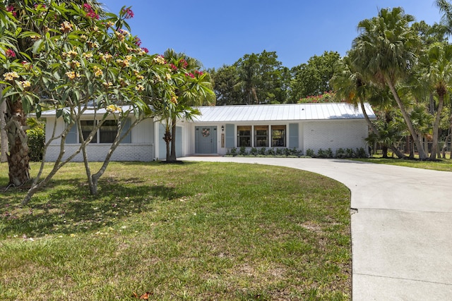 4972 S Kay St, Palm Beach Gardens, FL 33418 - view of front of home featuring brick siding, a front lawn, and curved driveway