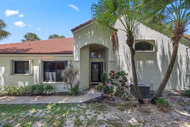 703 Sea Oats Dr Unit A-5, Juno Beach, FL 33408 - view of exterior entry with a tile roof, stucco siding, and central air condition unit