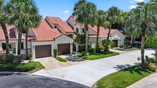 703 Sea Oats Dr Unit A-5, Juno Beach, FL 33408 - mediterranean / spanish-style home featuring stucco siding, a tile roof, driveway, and a garage