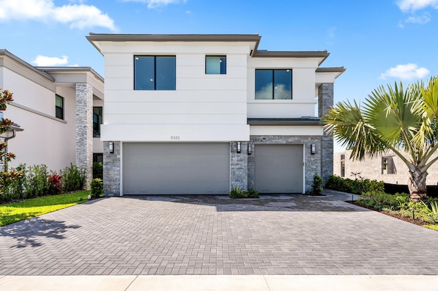 8342 Crystal Downs Ave, Boca Raton, FL 33434 - modern home featuring stone siding, an attached garage, and decorative driveway
