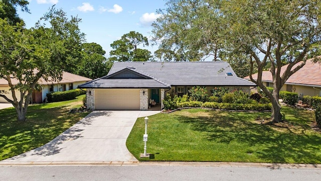 1345 SW Cedar Cv E, Port Saint Lucie, FL 34986 - view of front facade with an attached garage, stone siding, concrete driveway, and a front lawn