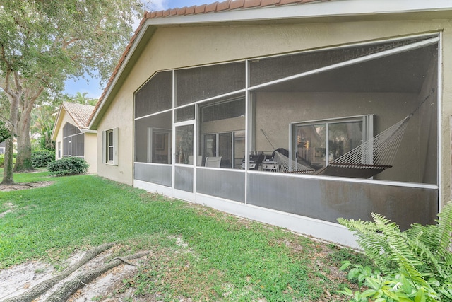 12092 Aprilia Dr, Boynton Beach, FL 33437 - back of house featuring stucco siding, a tiled roof, a sunroom, and a lawn