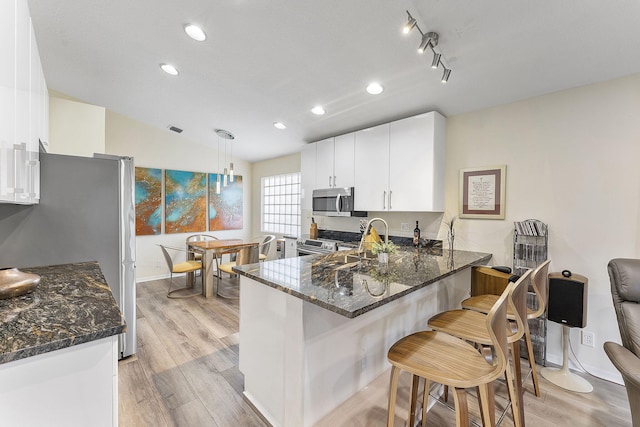 12092 Aprilia Dr, Boynton Beach, FL 33437 - kitchen with appliances with stainless steel finishes, light wood finished floors, dark stone counters, a peninsula, and recessed lighting