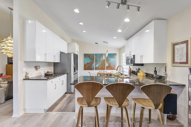 12092 Aprilia Dr, Boynton Beach, FL 33437 - kitchen featuring appliances with stainless steel finishes, light wood-style flooring, recessed lighting, a peninsula, and a kitchen bar