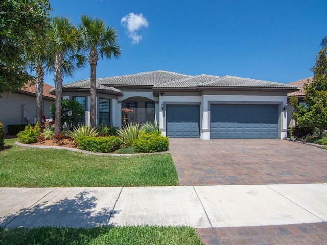 5082 Monroe Cir, Vero Beach, FL 32967 - view of front of house with a tile roof, stucco siding, a garage, decorative driveway, and a front yard
