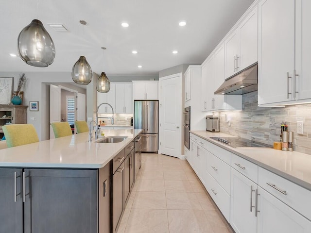 5082 Monroe Cir, Vero Beach, FL 32967 - kitchen with under cabinet range hood, stainless steel appliances, a sink, backsplash, and white cabinetry