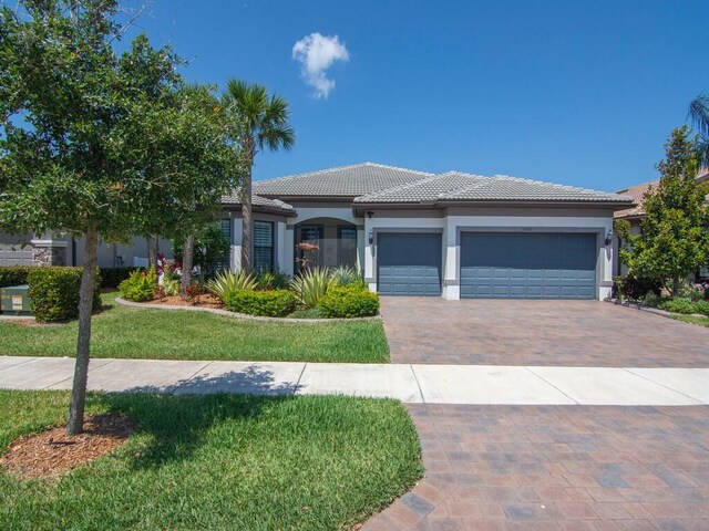 5082 Monroe Cir, Vero Beach, FL 32967 - view of front of property with a tile roof, stucco siding, decorative driveway, a garage, and a front yard