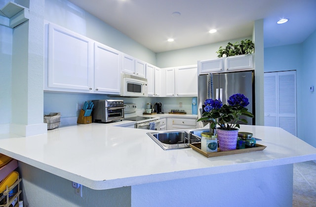1406 W Wickham Cir Unit A, Delray Beach, FL 33445 - kitchen with white appliances, a peninsula, white cabinetry, a kitchen bar, and recessed lighting