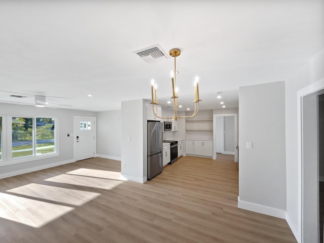 417 Philadelphia Dr, Jupiter, FL 33458 - kitchen with stainless steel appliances, light wood-style flooring, baseboards, a chandelier, and white cabinets