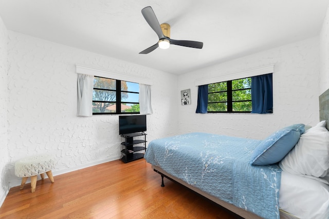 bedroom featuring baseboards, wood finished floors, and a ceiling fan
