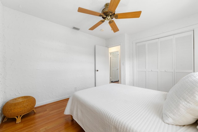 bedroom featuring wood finished floors, baseboards, a closet, and ceiling fan
