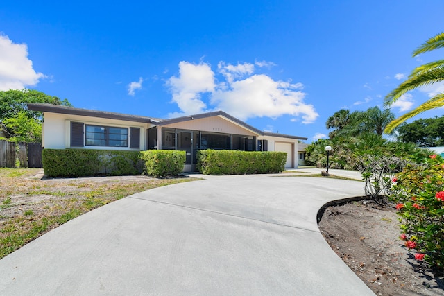 single story home with a garage, concrete driveway, and a sunroom