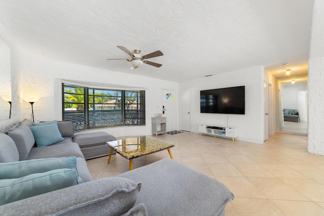 living area featuring light tile patterned floors, ceiling fan, and a textured ceiling