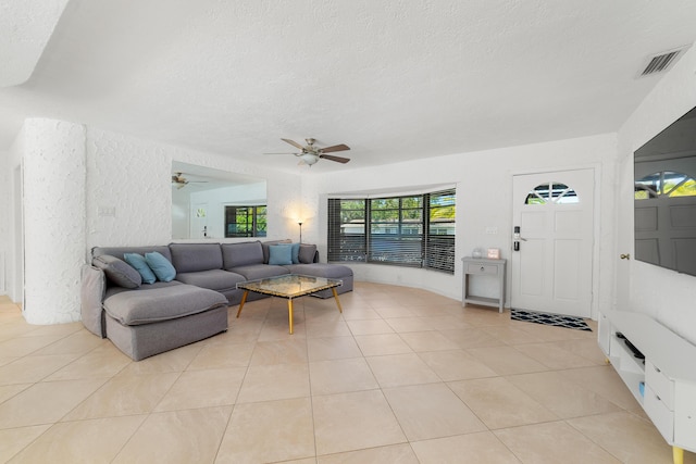 living area with a textured ceiling, a ceiling fan, and light tile patterned floors