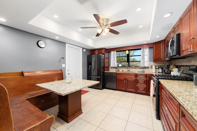 kitchen featuring black appliances, a sink, tasteful backsplash, ceiling fan, and a raised ceiling