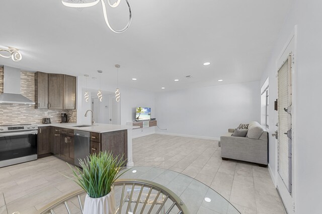 234 Capri E, Delray Beach, FL 33484 - kitchen with wall chimney exhaust hood, appliances with stainless steel finishes, open floor plan, dark brown cabinets, and light countertops