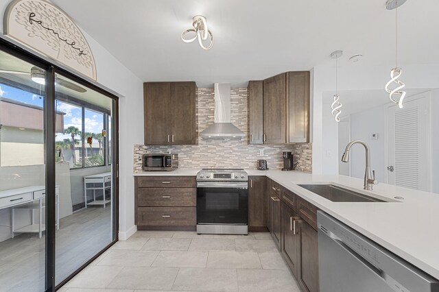 234 Capri E, Delray Beach, FL 33484 - kitchen with wall chimney range hood, stainless steel appliances, a sink, light countertops, and decorative backsplash