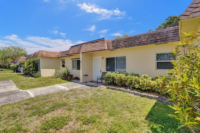 3647 SW Natura Ave Unit B, Deerfield Beach, FL 33441 - rear view of property with mansard roof, stucco siding, a lawn, and roof with shingles