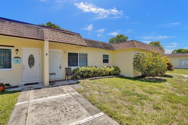 3647 SW Natura Ave Unit B, Deerfield Beach, FL 33441 - doorway to property with mansard roof, roof with shingles, stucco siding, and a lawn