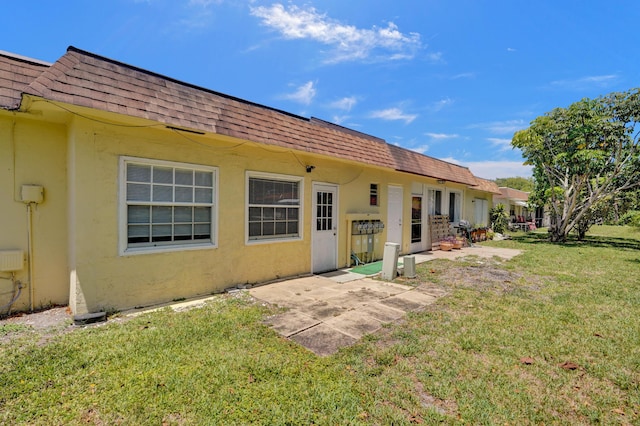 3647 SW Natura Ave Unit B, Deerfield Beach, FL 33441 - back of house with roof with shingles, mansard roof, stucco siding, a yard, and a patio