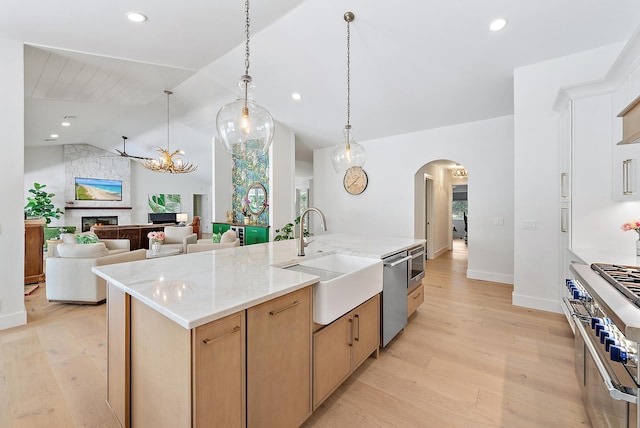6799 Imperial Woods Rd, Jupiter, FL 33458 - kitchen with a sink, appliances with stainless steel finishes, arched walkways, a large fireplace, and light wood-style flooring