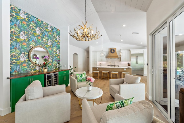 6799 Imperial Woods Rd, Jupiter, FL 33458 - living area featuring wine cooler, lofted ceiling, a chandelier, arched walkways, and light wood-style floors