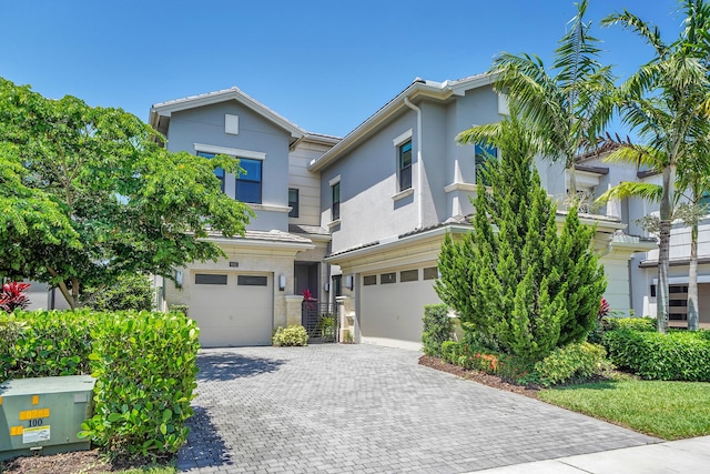 view of front of property with an attached garage, stucco siding, and decorative driveway