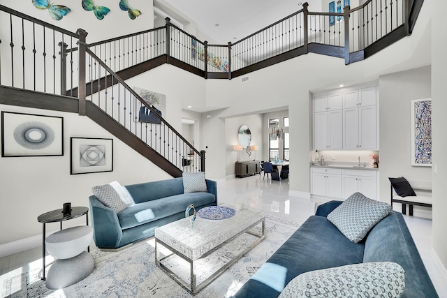 living room featuring a towering ceiling, stairs, and baseboards