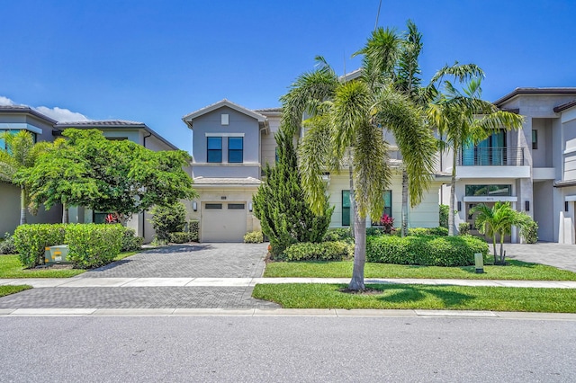 view of front of house with decorative driveway, an attached garage, and stucco siding