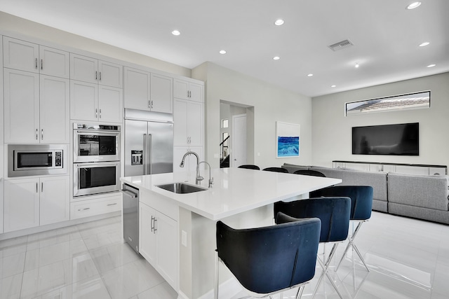 kitchen with a sink, built in appliances, open floor plan, recessed lighting, and light countertops