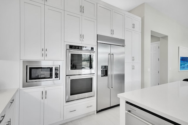 kitchen with built in appliances, light countertops, and white cabinetry