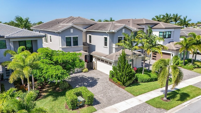 view of front of property with decorative driveway, a garage, stucco siding, a tiled roof, and a residential view